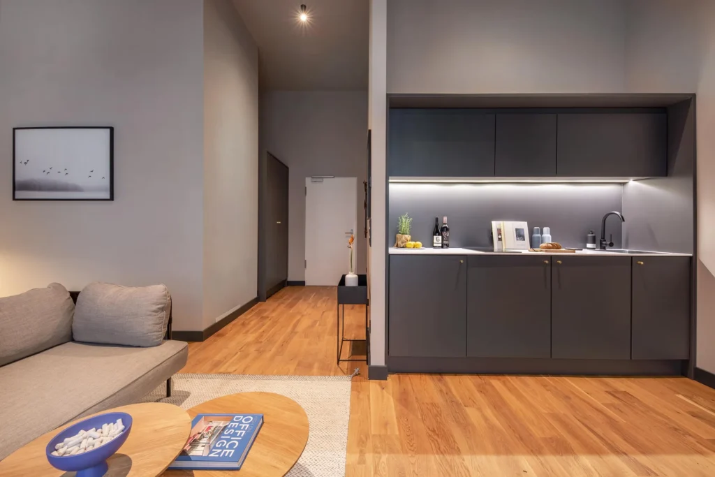 Dark kitchen area with niche, sofa and coffee table in the high space of the Luxury apartment, ipartment Hamburg Eimsbüttel