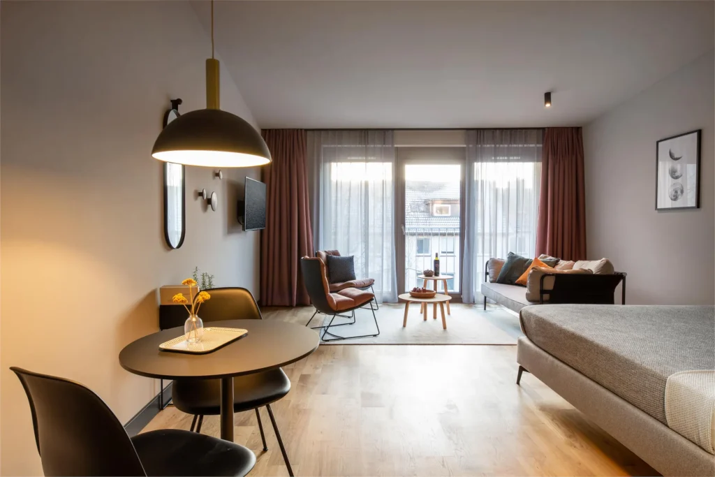 Wohn- und Schlafbereich mit Essplatz, Sofa und Fenstertür zum Balkon im Apartment Medium, ipartment Hamburg Eimsbüttel