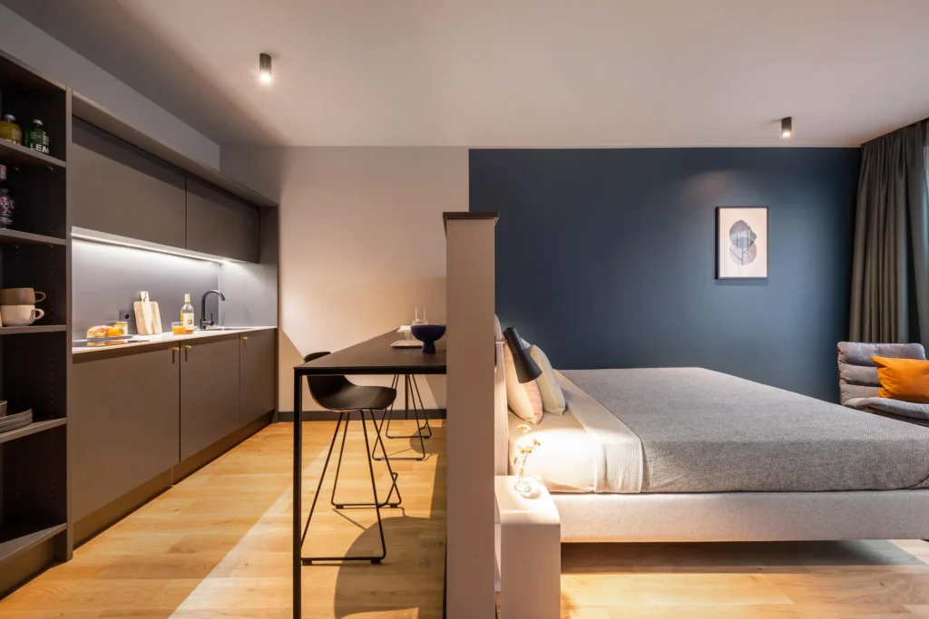 Double bed with a partition, kitchenette and high table in the Smart apartment, ipartment Hamburg Eimsbüttel