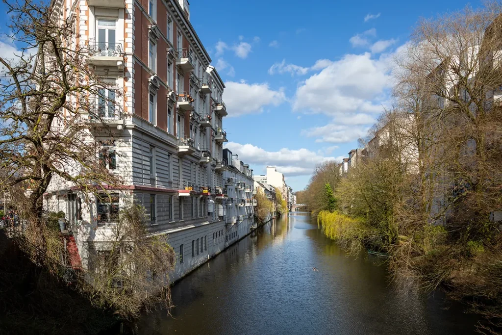 Channel with early-era houses and trees under a blue sky in Hamburg Eimsbüttel