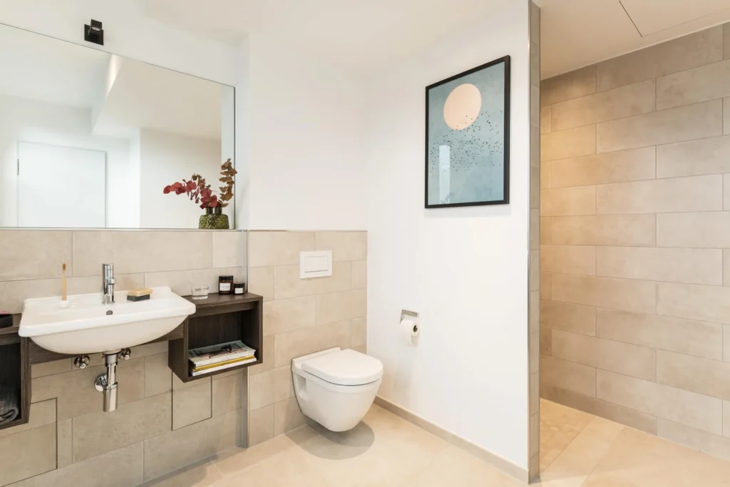 Bathroom with sink, mirror and picture on the tiled wall in apartment M, ipartment Hamburg HafenCity