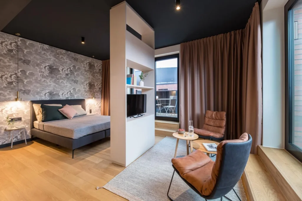 Sleeping area with room divider, leather chairs and access to the balcony in Apartment M, ipartment Hamburg HafenCity