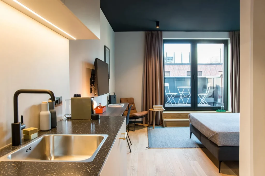 Kitchenette with sink, TV and balcony window in Apartment S, ipartment Hamburg HafenCity
