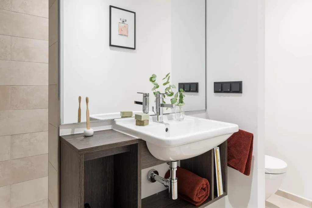 Bathroom with sink made of dark wood and mirror in the XS apartment, ipartment Hamburg HafenCity