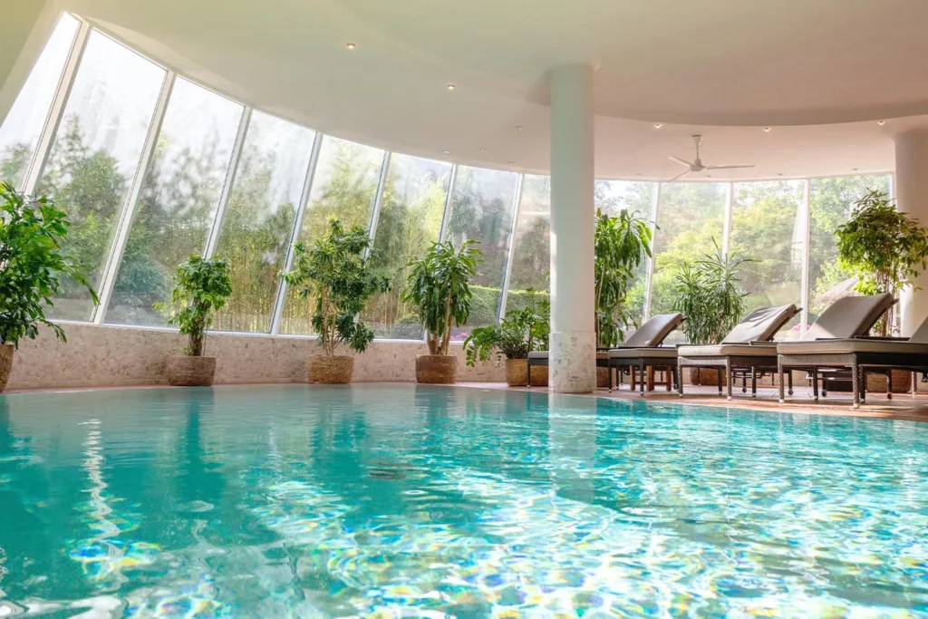 Swimming pool with sun loungers and plants at David Lloyd Meridian Spa & Fitness, Hamburg