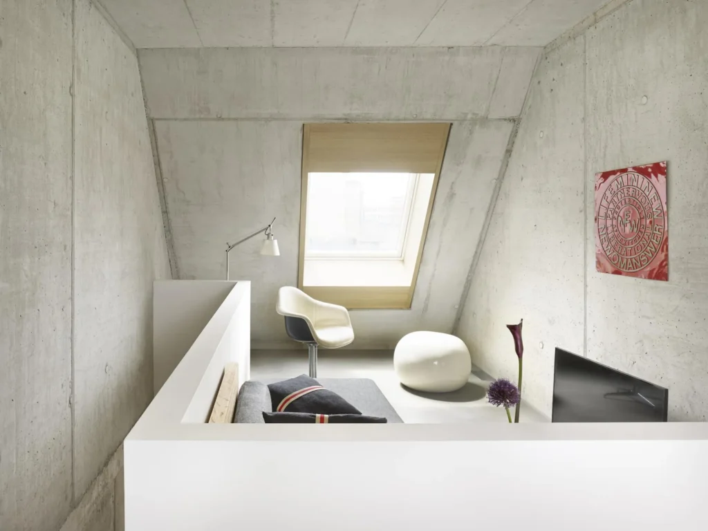 Gallery level with armchair, stool and skylight under the concrete roof in Apartment M, apartment Cologne Mülheim