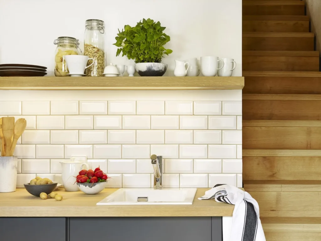 Kitchenette with white tiles, sink, wooden shelf and stairs in apartment M, ipartment Cologne Mülheim