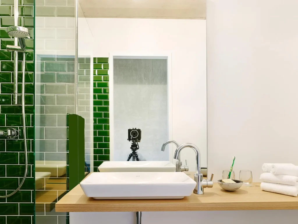 Bathroom with green tiled shower, sink and towels in apartment S, apartment Cologne Mülheim