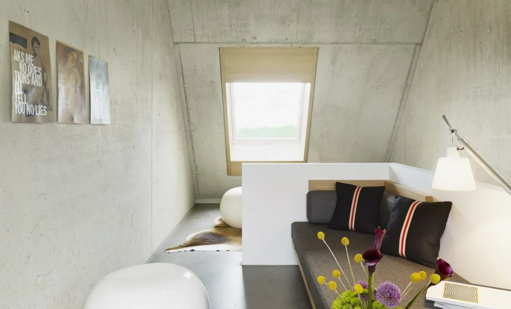 Gallery area with sofa, cushions and skylight under the concrete roof in apartment S, ipartment Cologne Mülheim