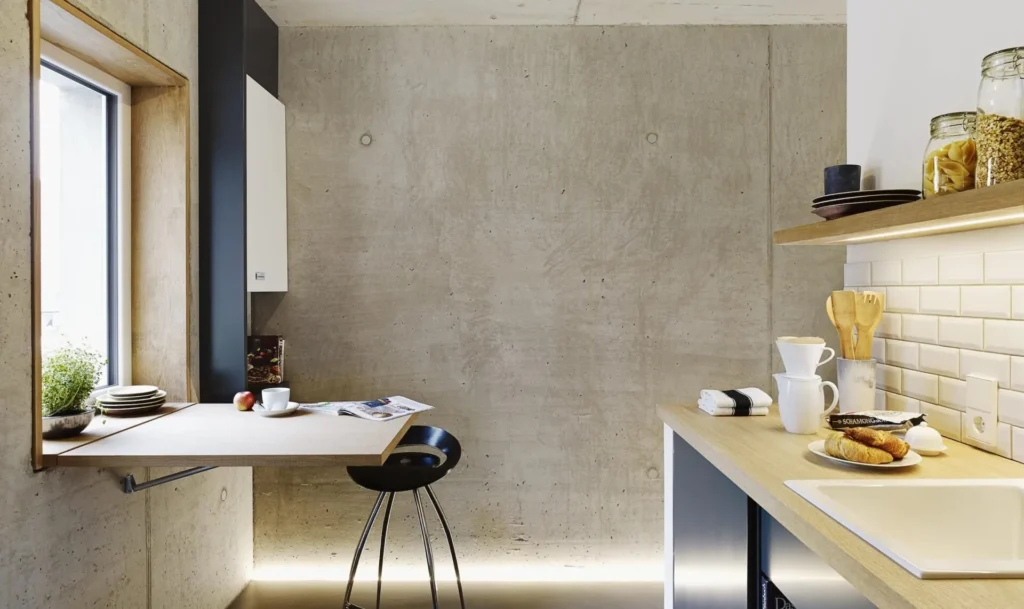 Kitchenette with white tiles and folding table by the window in the XS apartment, ipartment Cologne Mülheim