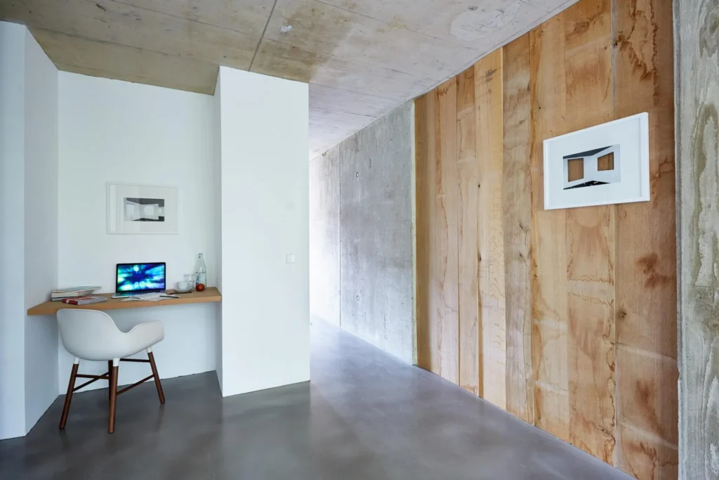 Desk with laptop and chair in front of a wall of oak wood in the XS apartment, ipartment Cologne Mülheim
