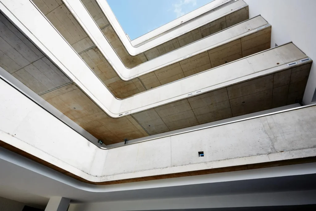 View up into the atrium with curved concrete balconies and sky, ipartment Cologne Mülheim