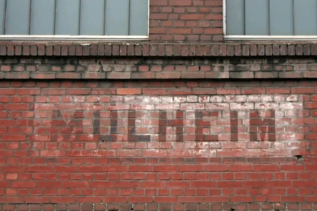 Red brick wall with faded white lettering MÜLHEIM on an industrial building in Cologne