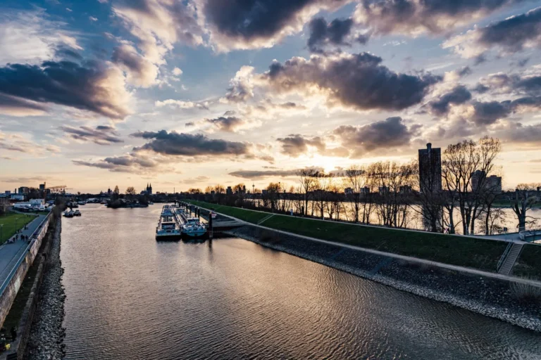 Evening sky over the Rhine with harbor basin, ships and waterfront promenade in Cologne