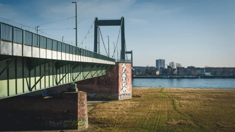 Suspended bridge over the Rhine with a riverside meadow and a view of the opposite bank in Cologne