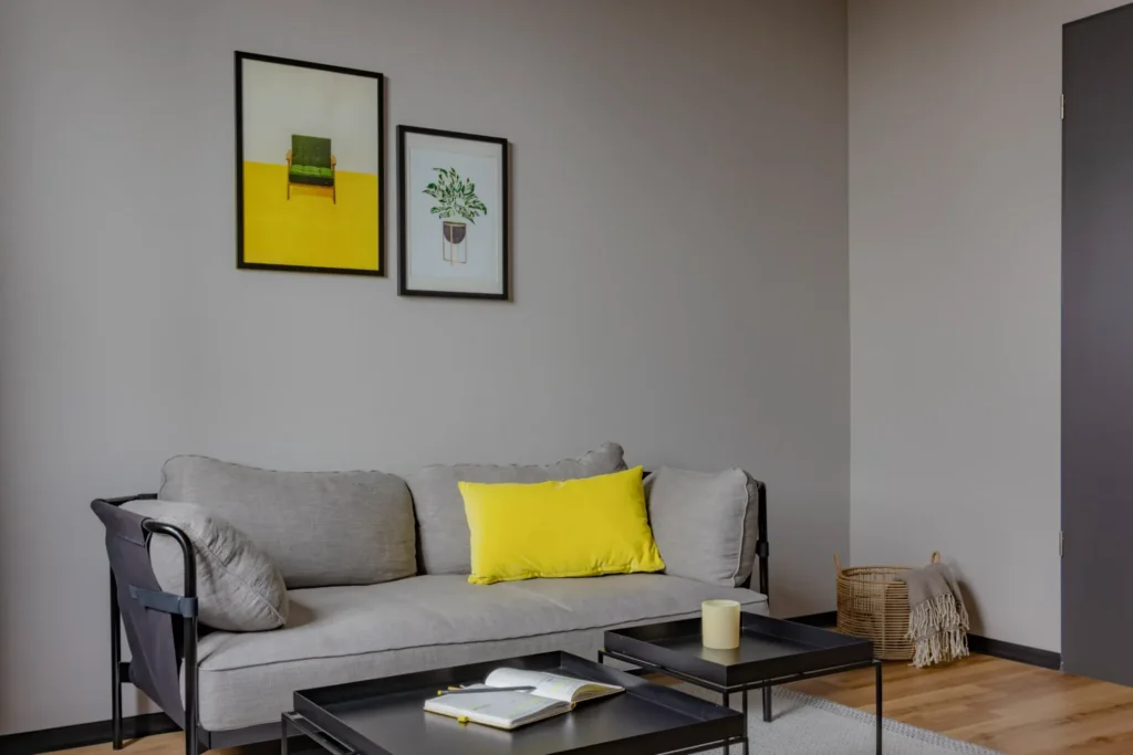 Gray sofa with yellow cushion, coffee tables and wall paintings in the living area in the Luxury apartment, ipartment Leverkusen