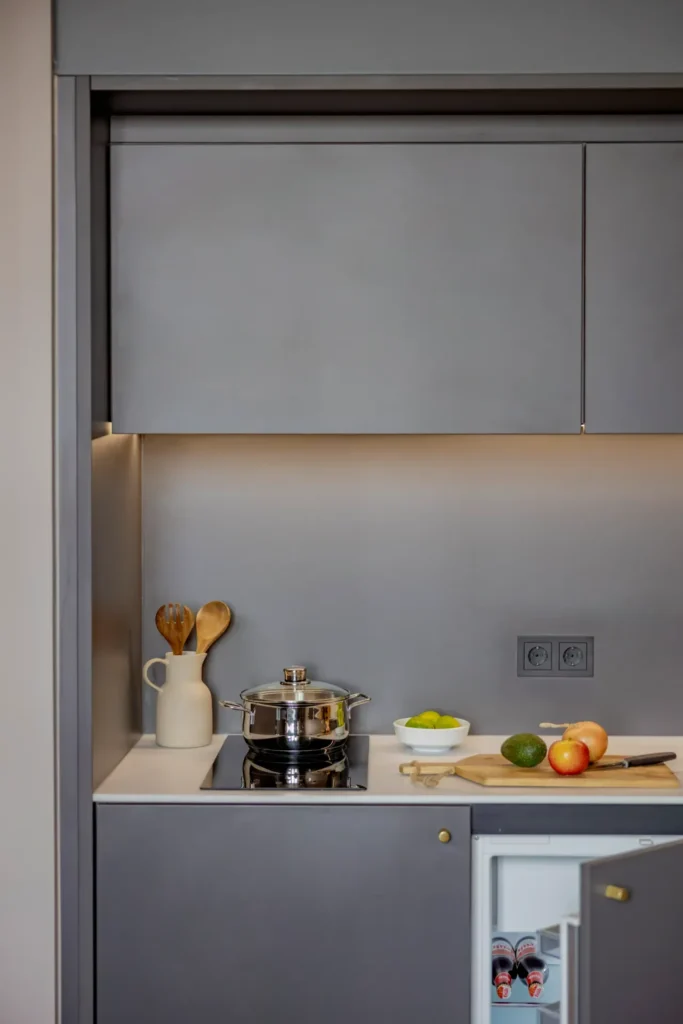 Kitchenette with stove, pot, fruit and refrigerator under the worktop in the Luxury apartment, ipartment Leverkusen
