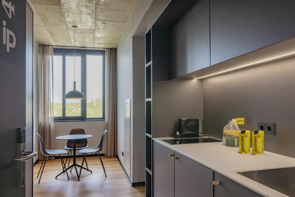 Kitchenette with cooking stove and small dining table with chairs in the Medium apartment, ipartment Leverkusen