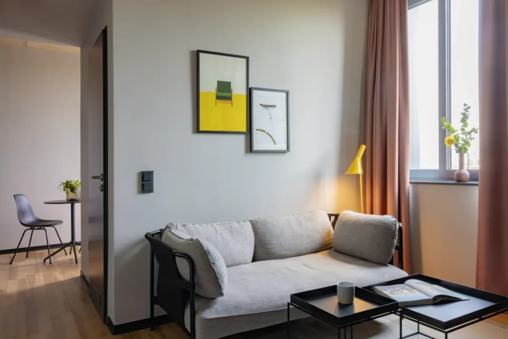 Gray sofa with coffee table, floor lamp and wall paintings in front of the window in the Medium apartment, ipartment Leverkusen