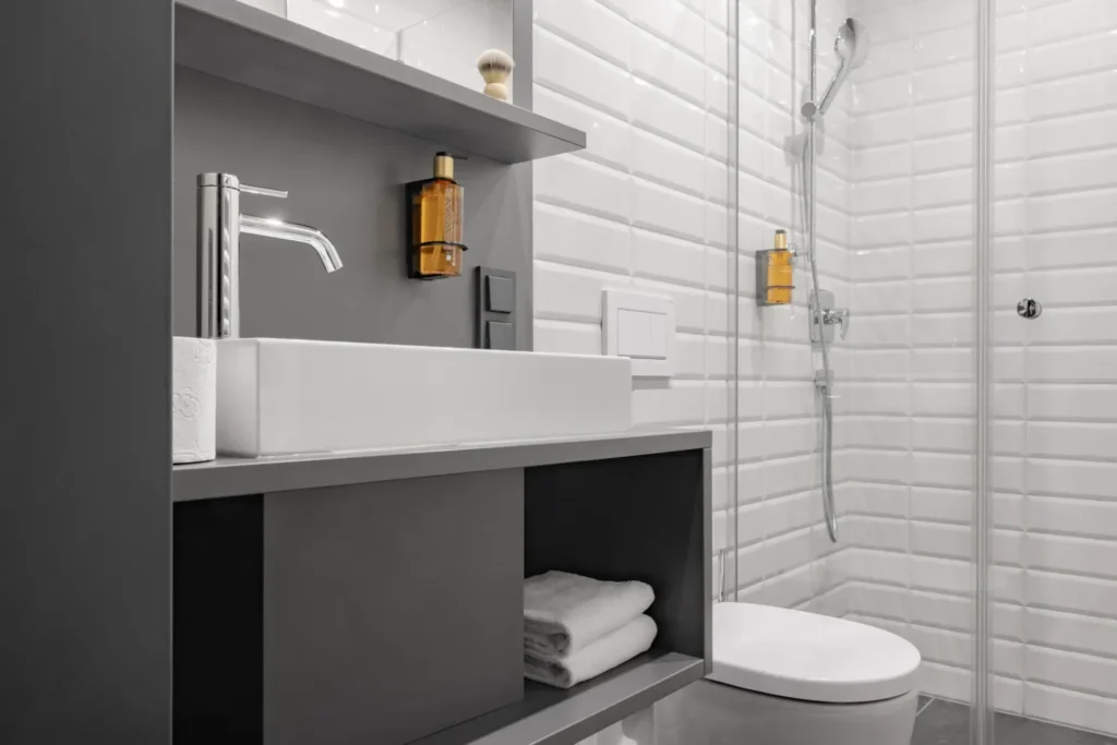 Bathroom with vanity sink, open shelf with towels and glass shower in the Medium apartment, ipartment Leverkusen