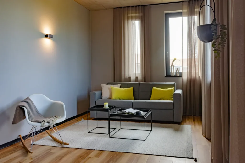 Living area with gray sofa, rocking chair, coffee tables and windows in the Xtra Luxury apartment, ipartment Leverkusen