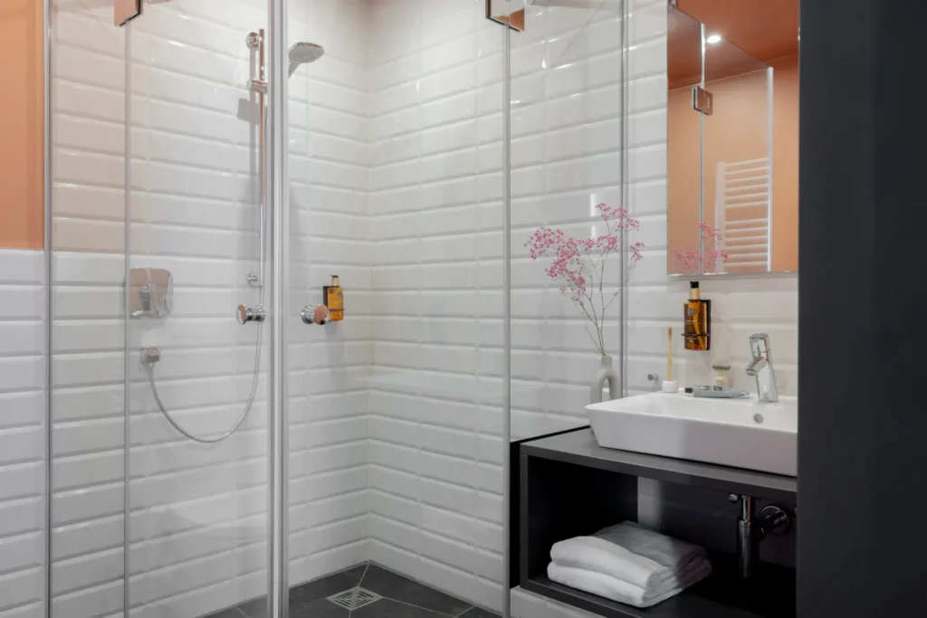 Bathroom with white subway tiles, glass shower, sink and towels in the Xtra Luxury apartment, ipartment Leverkusen