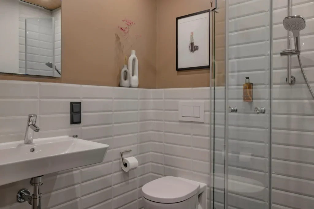 Bathroom with white subway tiles, sink, toilet and glass shower in the Xtra Smart apartment, ipartment Leverkusen