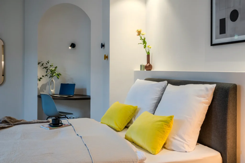 Double bed and desk in a niche with round arches, ipartment Wolfsburg