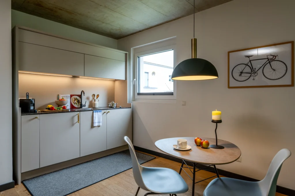 Kitchenette and round dining table under a pendant light, ipartment Wolfsburg