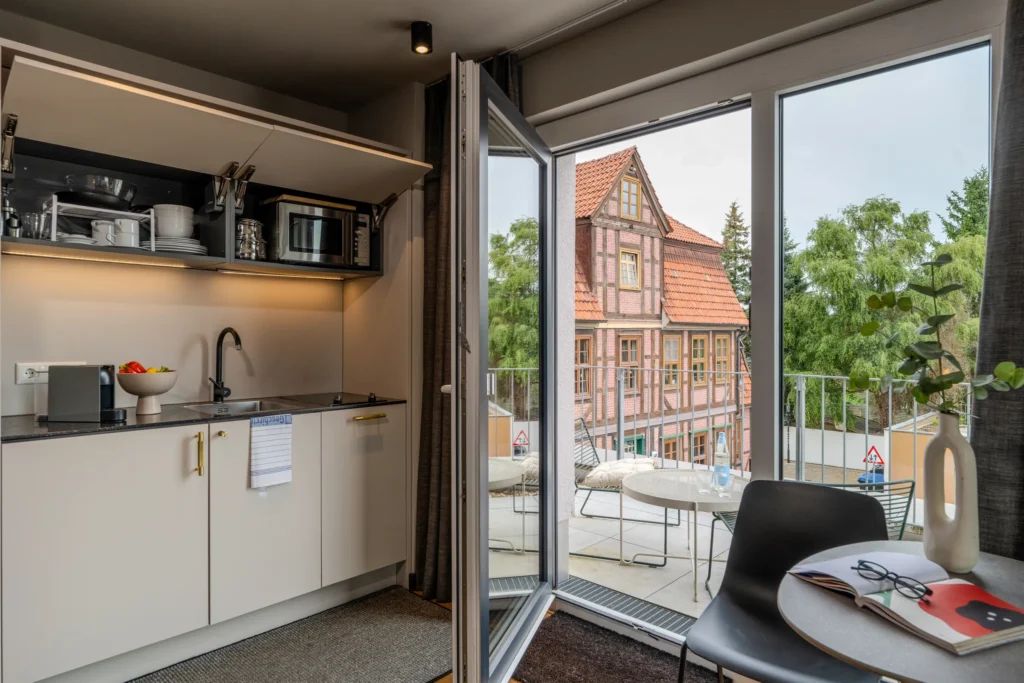 Kitchen area next to the open balcony door overlooking the half-timbered house, ipartment Wolfsburg