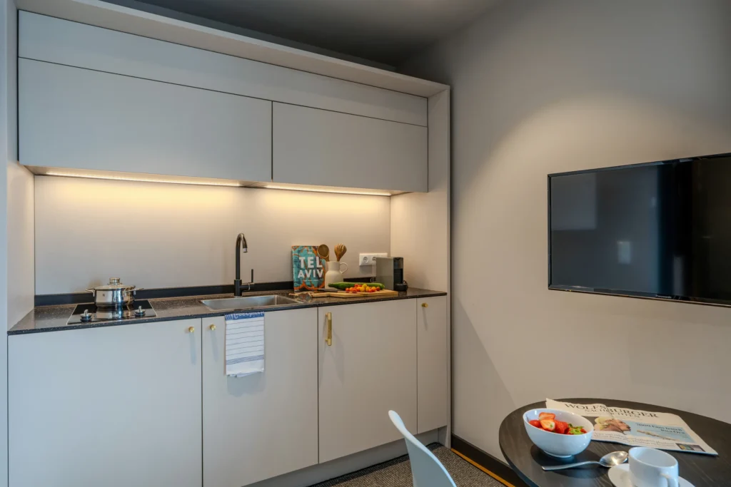 Kitchenette with stove and TV above the dining table, ipartment Wolfsburg