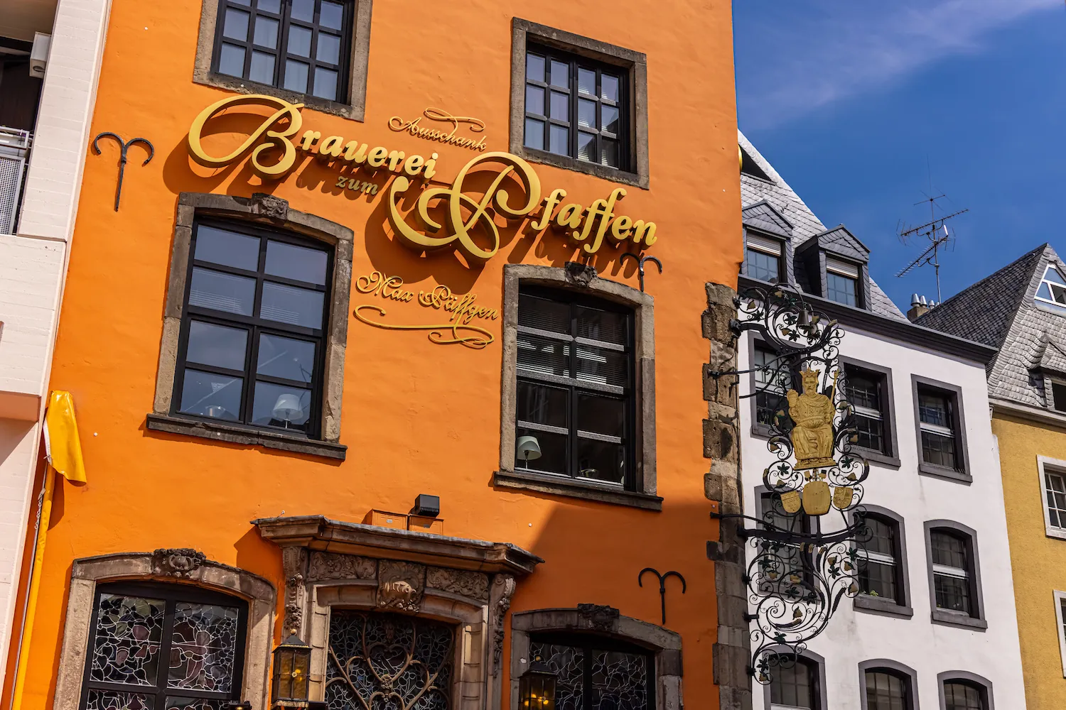 Orange Hausfassade mit goldenem Schriftzug „Brauerei zum Pfaffen“ und schmiedeeisernem Ausleger