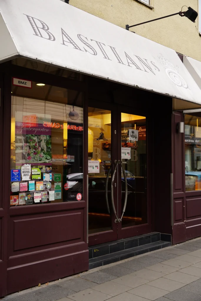 Eingang eines Cafés mit weißer Markise und dunkelroter Fassade.